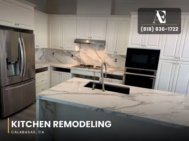 Calabasas kitchen remodel with white cabinets, a marble-look stone island, stainless refrigerator and built-in wall ovens