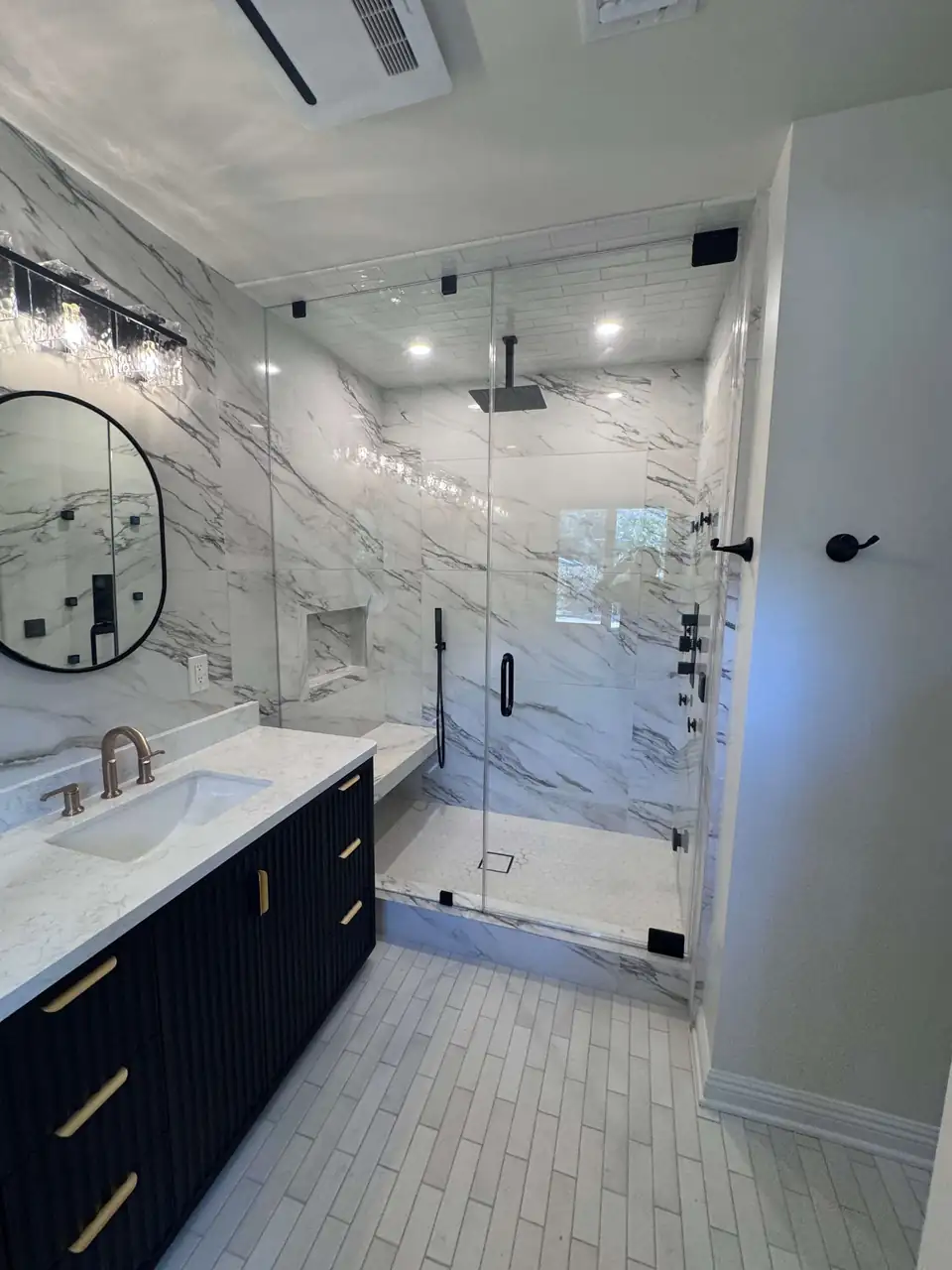 Bathroom remodeling in Westlake Village and nearby towns: frameless glass shower, marble-look wall tile and a navy vanity from a Santa Clarita project by All Exclusive Construction